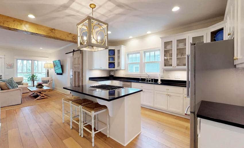 Cottage kitchen with charming black polished countertops and wood plank flooring