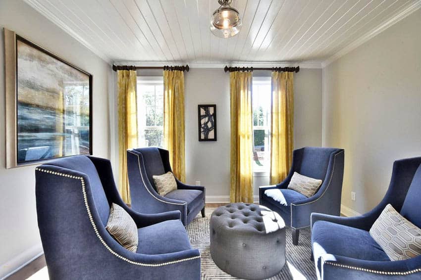 Room with mustard yellow curtains and blue wingback chair and grey table