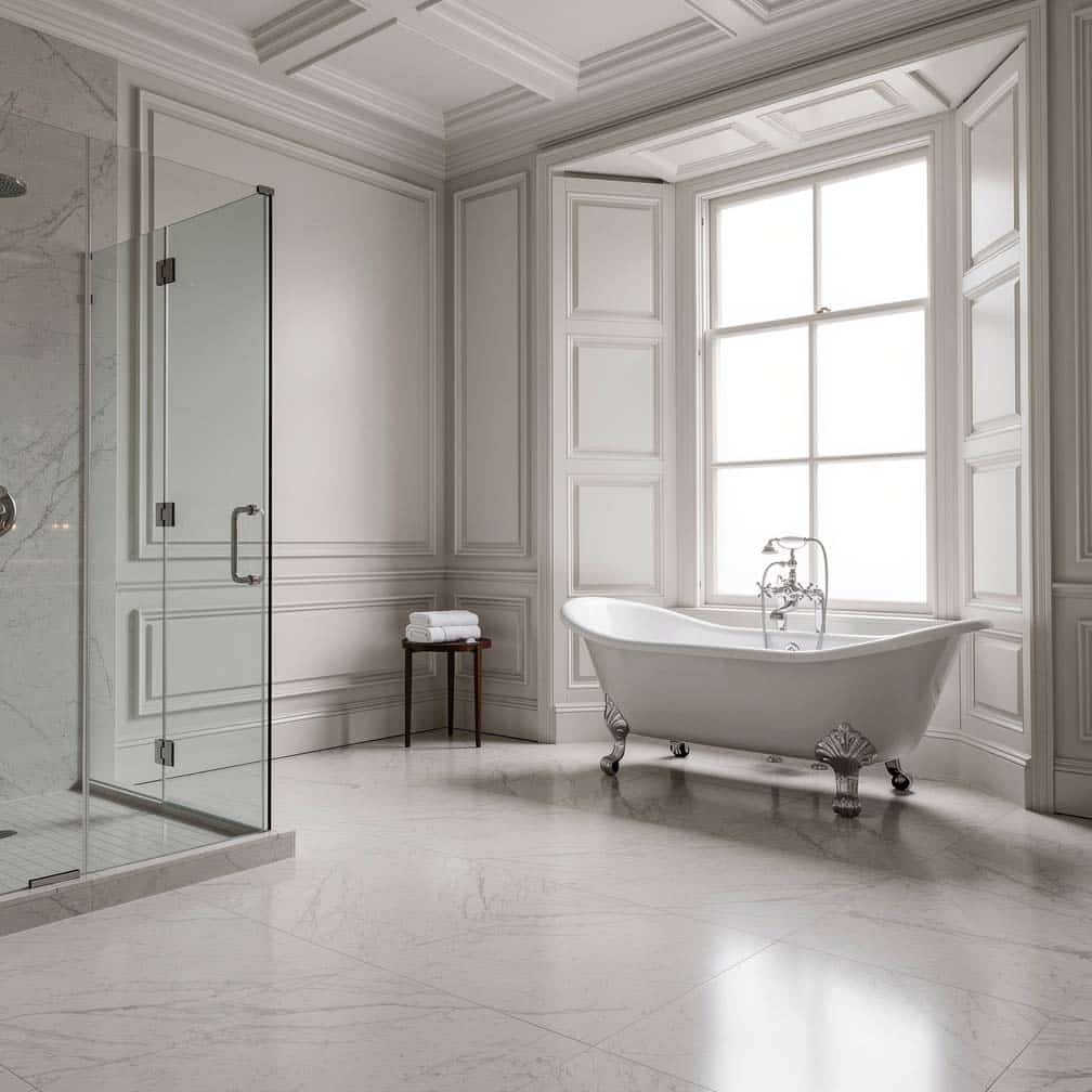 Floor-to-ceiling raised panel treatment with cast iron clawfoot bathtub and glass shower enclosure