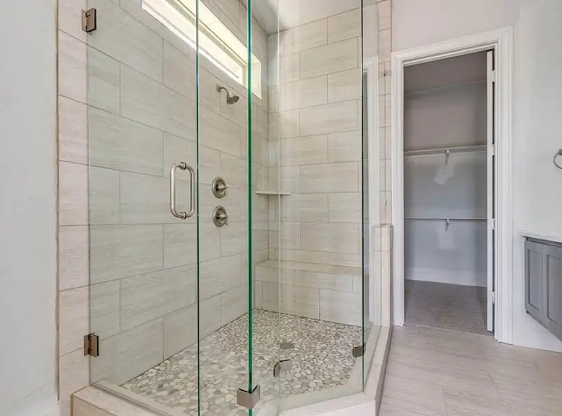 Bathroom with glass enclosure, shower, and bench