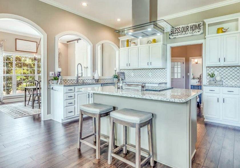 Beautiful kitchen with arabesque tile backsplash, white cabinets and hardwood flooring