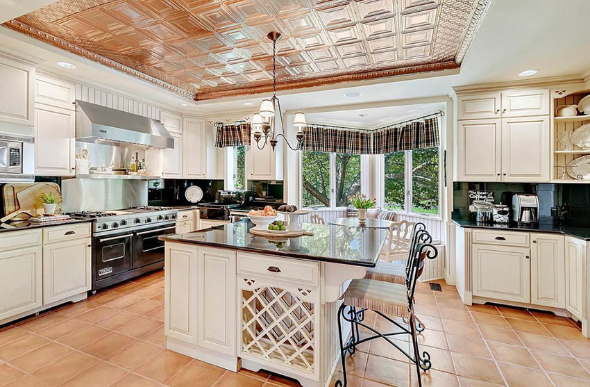 Kitchen with antique cream cabinets and granite surfaces with copper tray ceiling