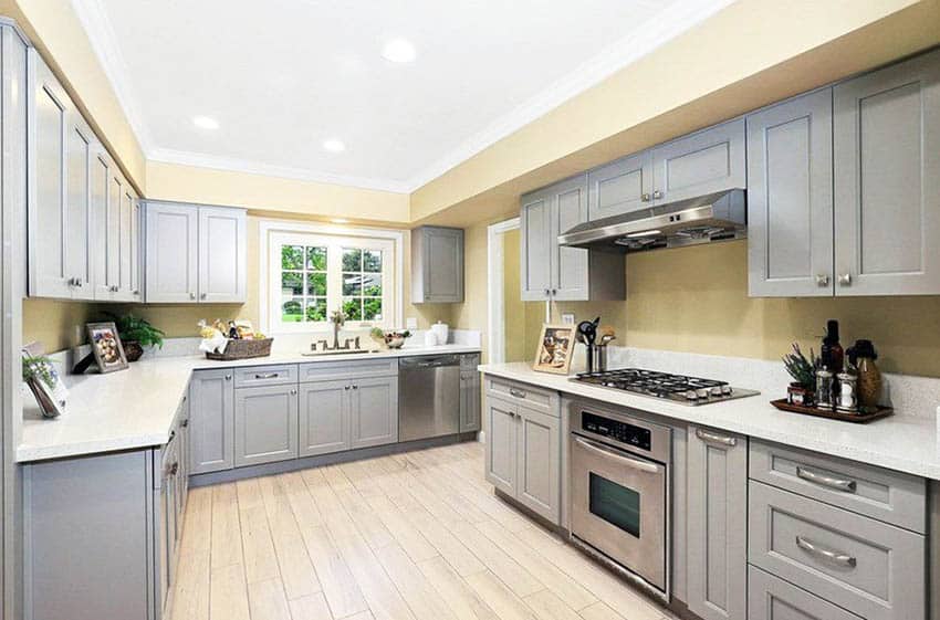 Kitchen with gray cabinets and yellow paint white quartz countertops wood look floor tile