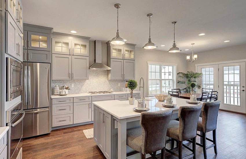 Kitchen with gray cabinets, white quartz countertops, white basketweave backsplash tile and wood floors