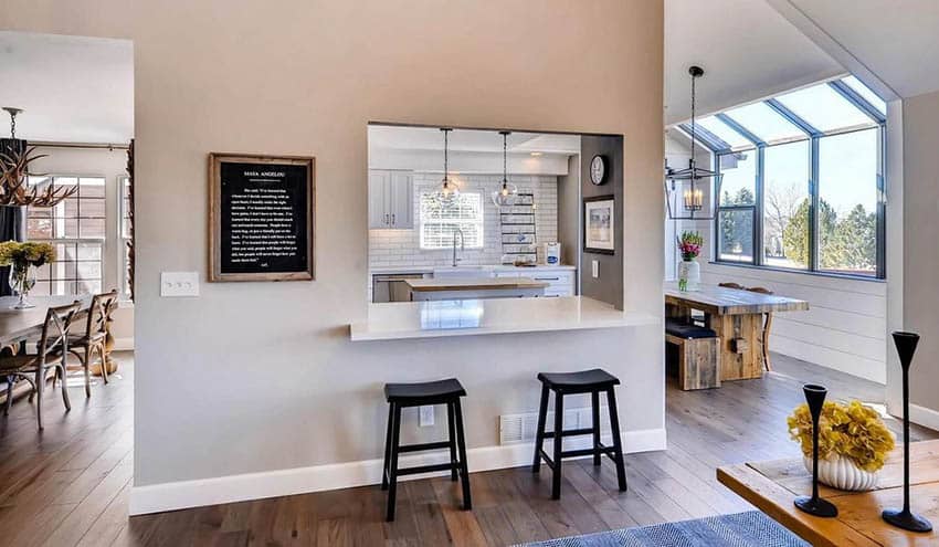 Kitchen with dining space, black stools and windows with sloed ceiling