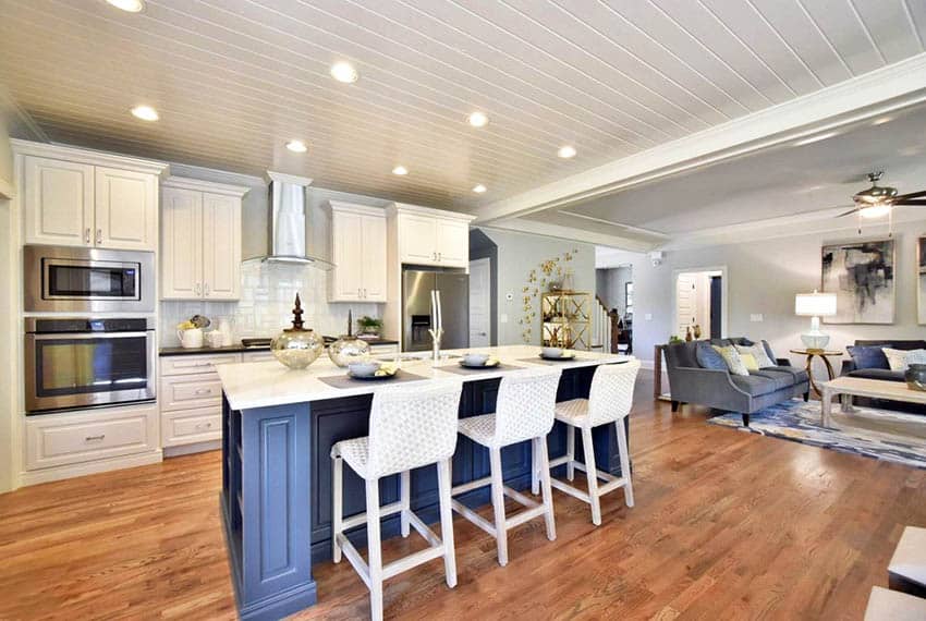 Kitchen with shiplap ceiling, white cabinets, blue island, white quartz countertop and wood flooring