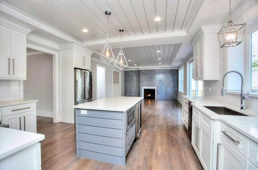 Kitchen with shiplap ceiling, white cabinets, blue shiplap island and white quartz countertop