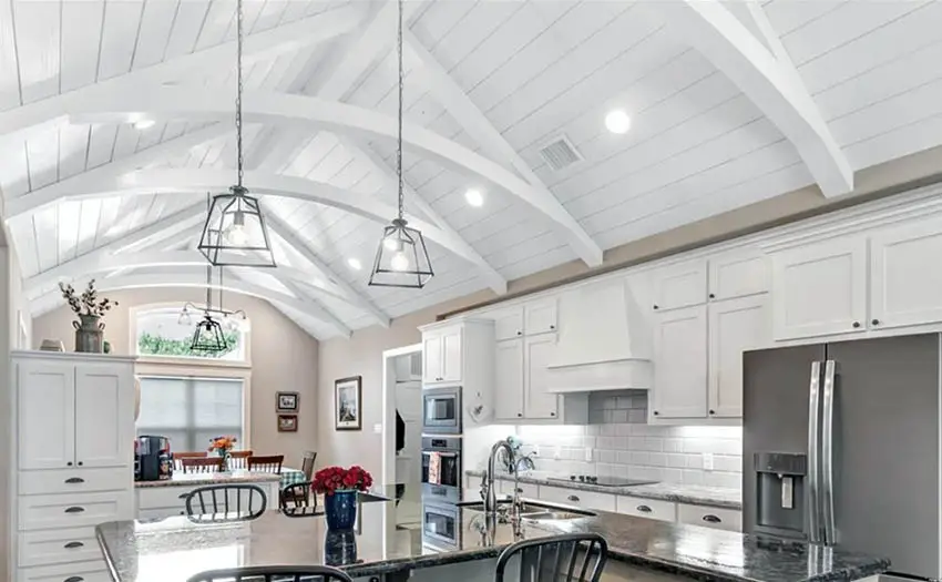 Kitchen with painted white vaulted ceiling, recessed lights and pendant lights over island