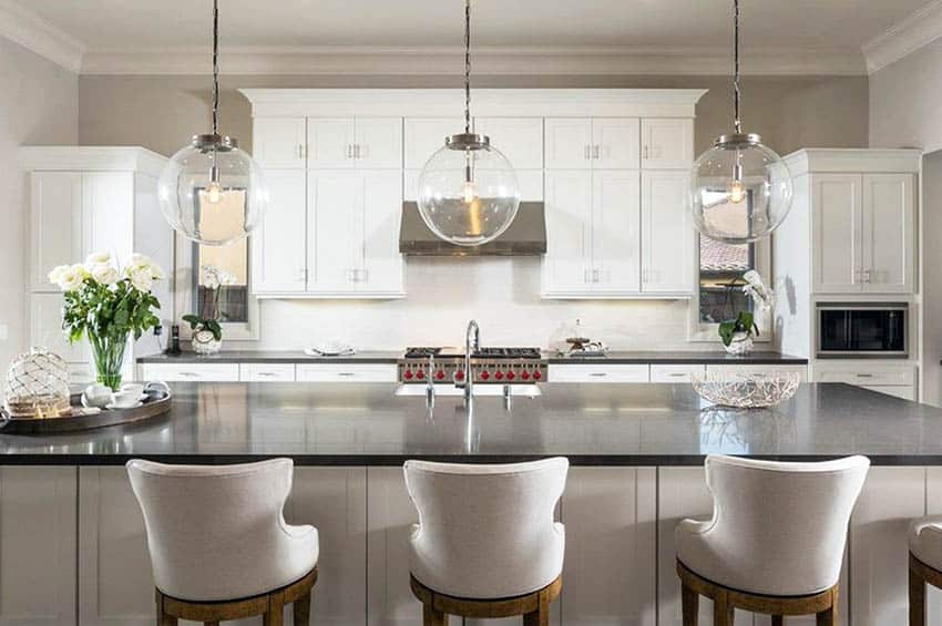 White staggered cabinets and black expansive quartz on island, and globe pendant lights