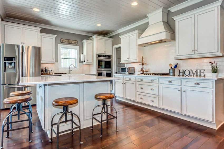 Kitchen with brown seat stools, white range hood and cherrywood floors