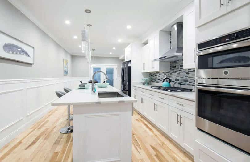 Kitchen with white wainscoting white cabinets wood flooring