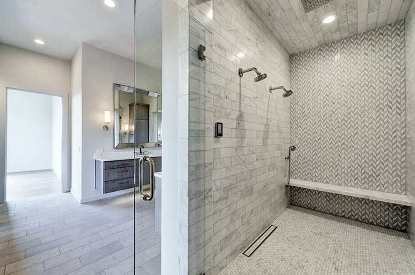 Large walk in shower with bench marble subway tiles and chevron design porcleian tile walls and penny tile flooring