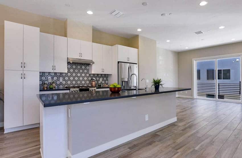 Modern open kitchen plan, white flat panel cabinets, black main countertops and gray island