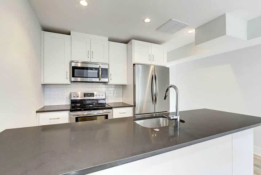 Small kitchen with dark grey countertops, white subway tile backsplash and peninsula