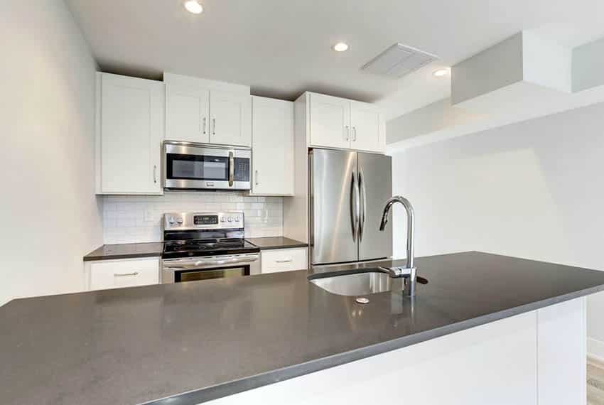 Small kitchen with smoke grey countertops, white subway tile backsplash and peninsula