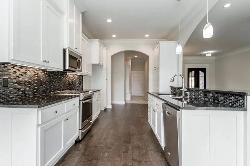 White kitchen cabinets with black granite countertops and backsplash