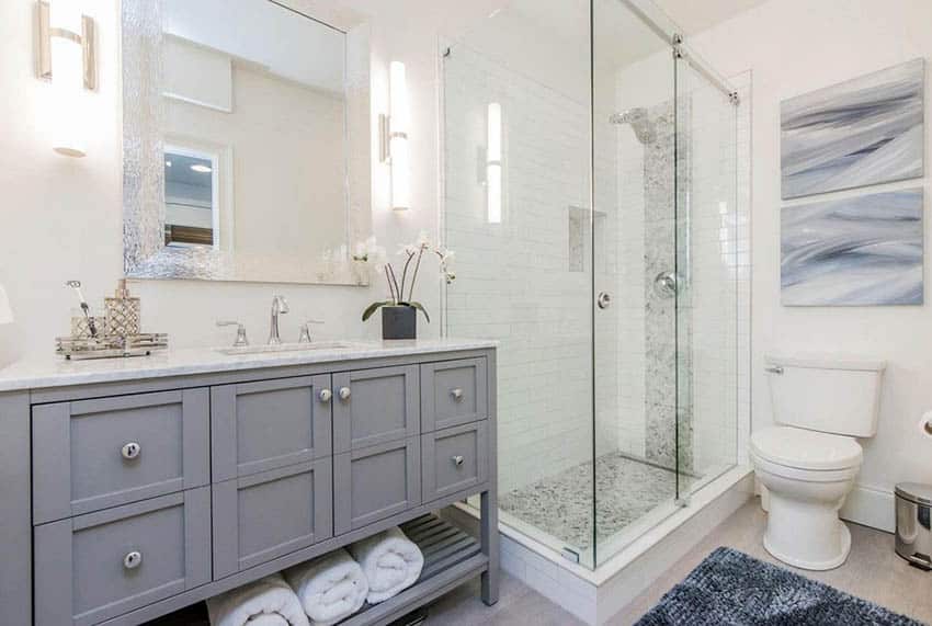 Bathroom with long white subway tile shower mosaic tile inlay gray vanity and porcelain tile floors