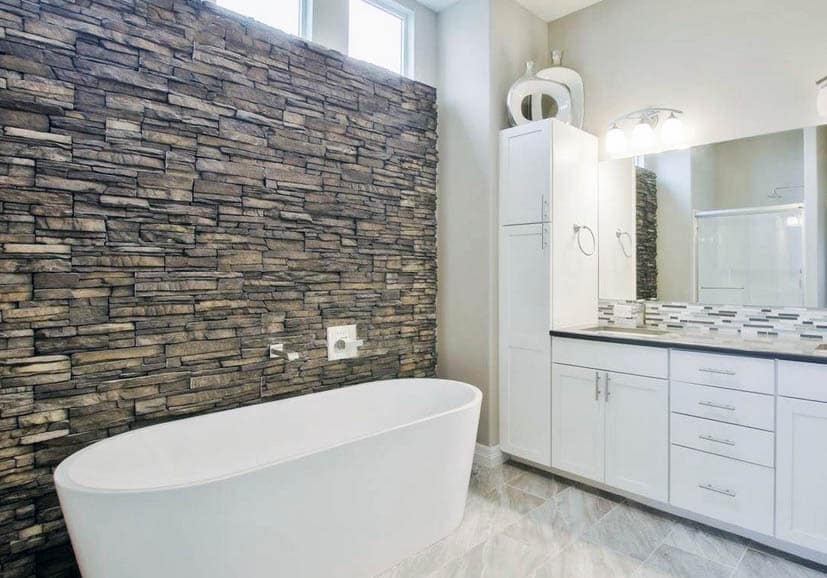 Bathroom with stacked stone accent wall and freestanding tub