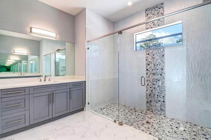 Mosaic pattern tiles on shower floor and walls and white vanity