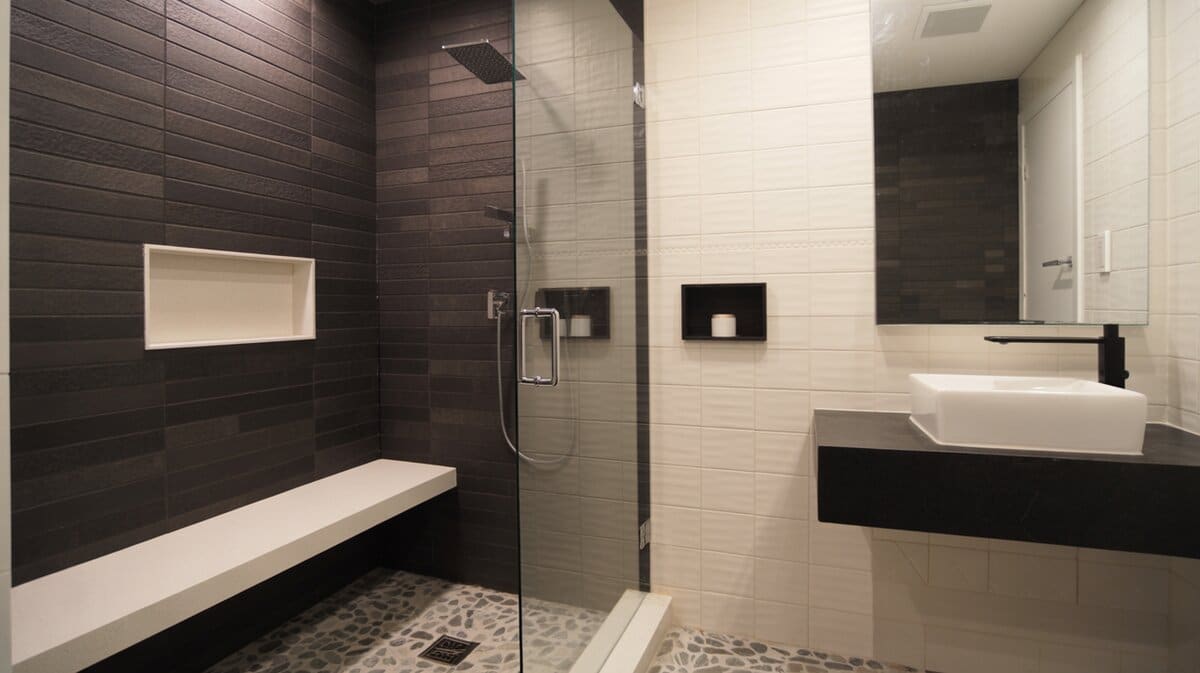 Contemporary bathroom with dark charcoal tile shower, white quartz built-in bench, and black floating vanity