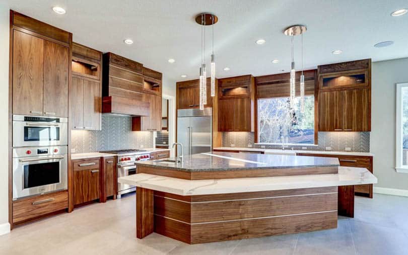 Kitchen with walnut cabinets, grey backsplash and chandelier