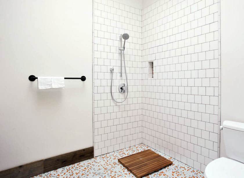 Doorless walk in shower with sprayer and white square tile