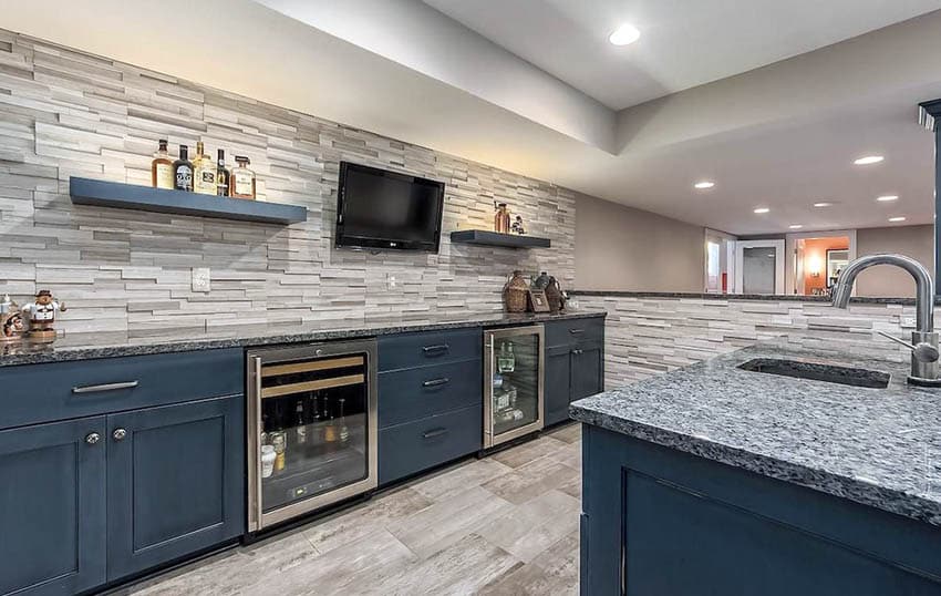 Home bar with stacked stone walls, navy blue cabinets and beige granite countertops