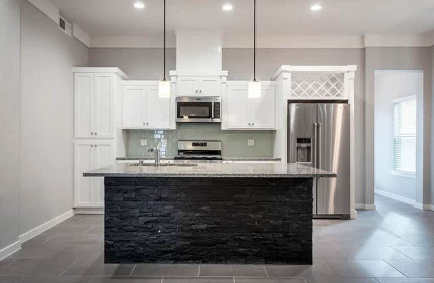 Kitchen with black stone panel island, white cabinets and porcelain floors
