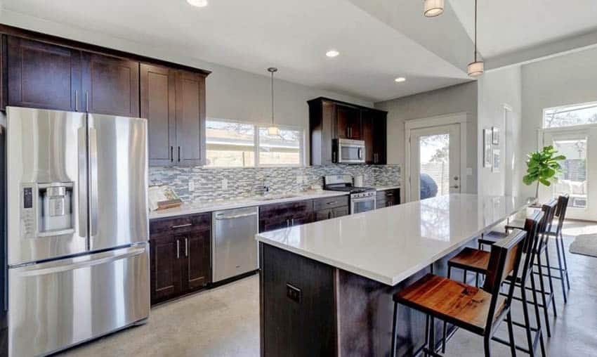 Kitchen with concrete flooring, brown cabinets and quartz island