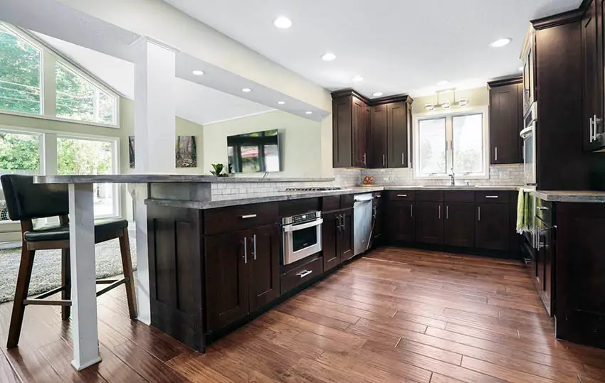 Kitchen with cork flooring and dark cabinets with breakfast bar peninsula