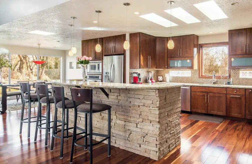 Kitchen with stone drywall island, brown chairs and wood cabinets