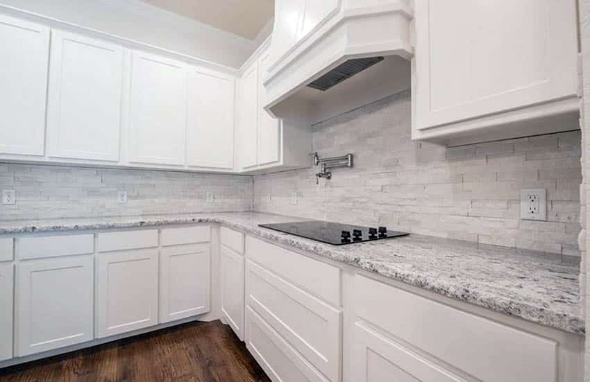 Kitchen with white stacked stone backsplash and white cabinets