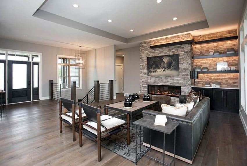 Room with stacked stone fireplace, grey couch and accent wall