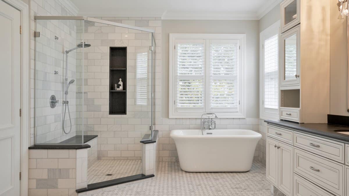 Luxury marble corner shower with small black granite built-in bench and freestanding soaking tub