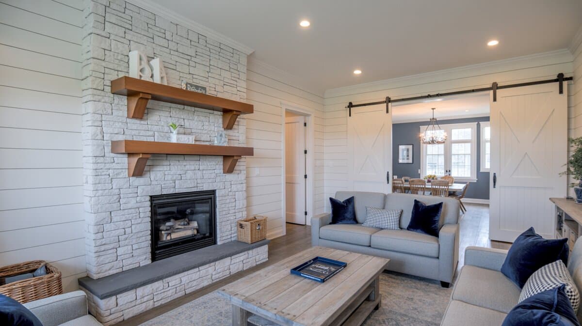 Farmhouse living room with white stacked stone fireplace and sliding barn door beyond