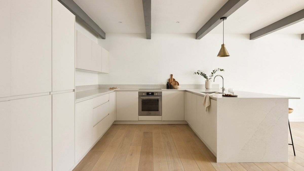 Handleless white MDF cabinets beneath a faux beam ceiling beside a wet bar
