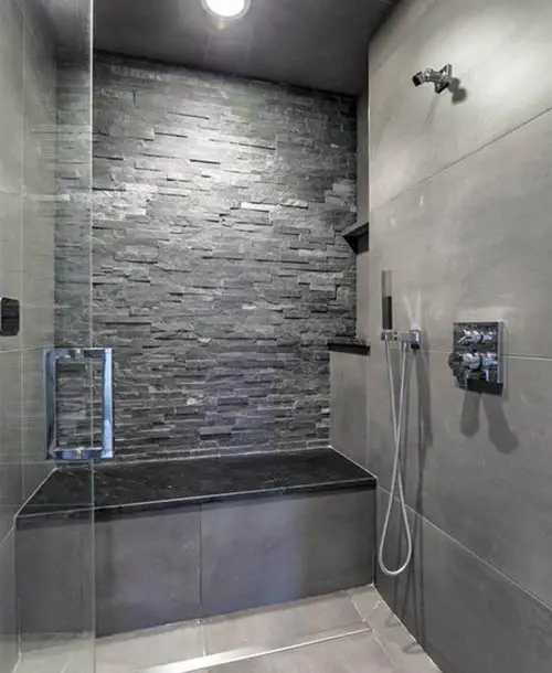 Shower with stacked stone accent wall and black granite bench 