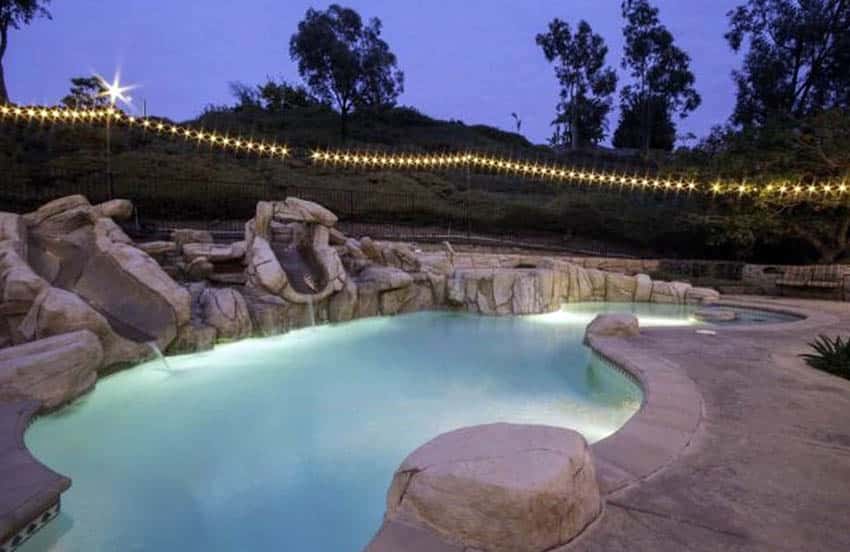 Swimming pool with string lights on poles