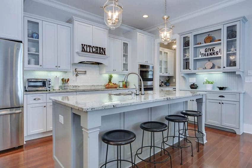 Kitchen with white painted cabinets, gray island, and oak flooring