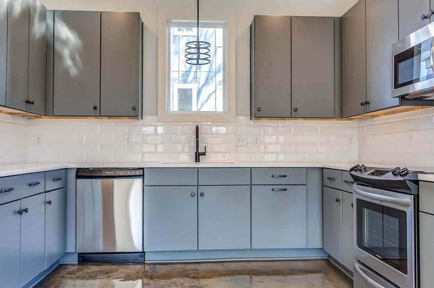 U shaped kitchen with white framed window, gray cabinets and stainless steel appliances