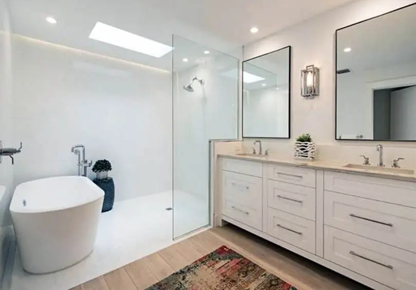 Bathroom with cabinets in antique white finish and skylight