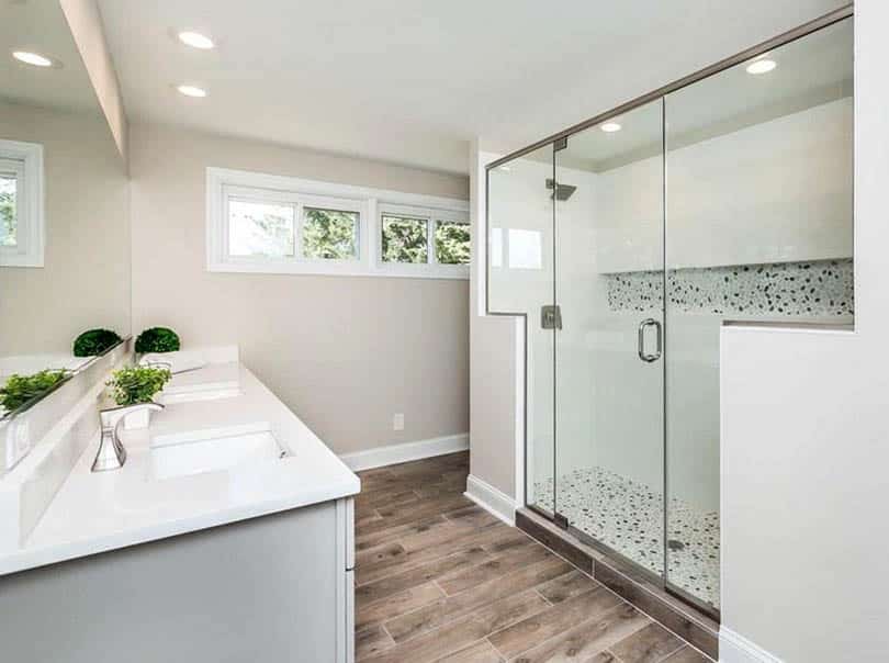 Walk in shower with stone tile alcove, quartz surround and t shaped glass design