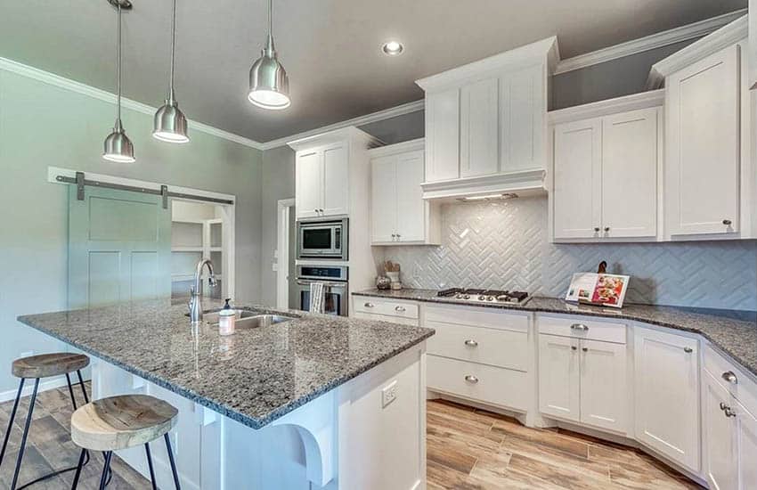 Kitchen with beveled backsplash, stool with wood seating and chrome ceiling lights