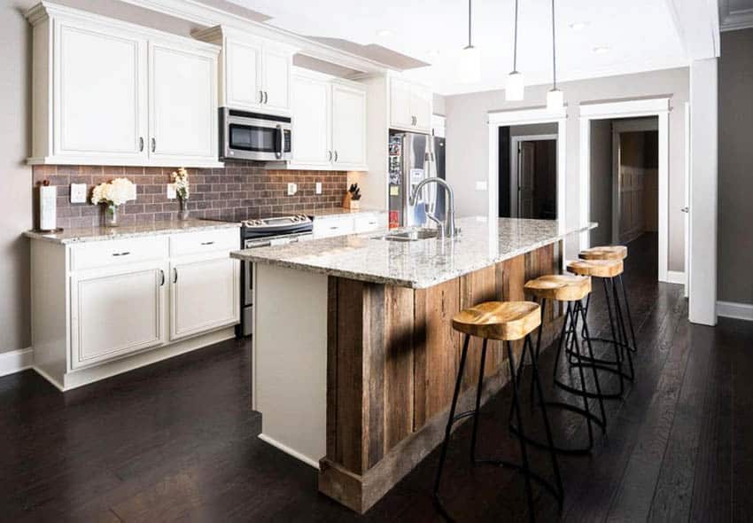 Kitchen with brown ceramic subway tile backsplash white raised panel cabinets and distressed wood island