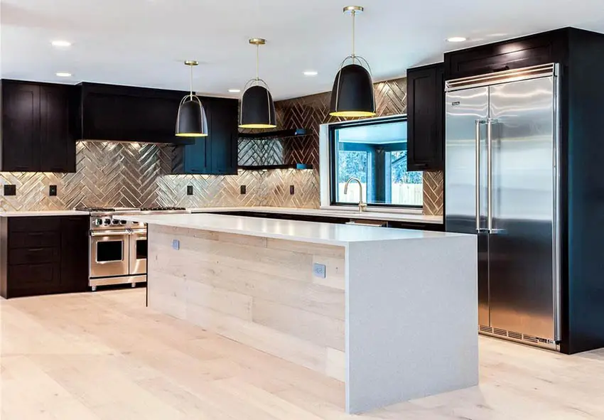 Kitchen with glazed brown tile with herringbone pattern, wood plank island and waterfall countertop