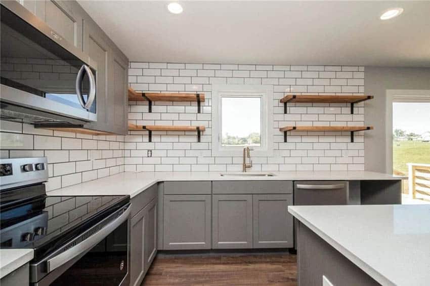 Kitchen with gray cabinets white subway tile with offset pattern and quartz countertops