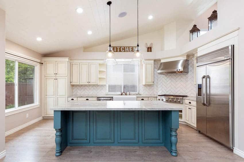 Kitchen island with blue paneled base and white counter, two door refrigerator and picture window