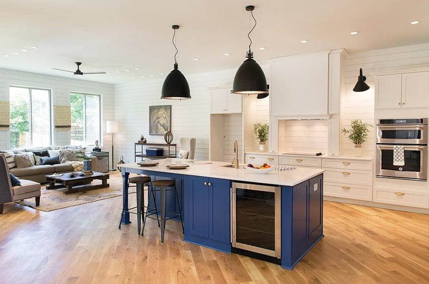 Kitchen with shiplap walls, white cabinets, blue island and wood flooring