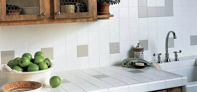 Kitchen with gray and white square tiles ans a bowl of green apples 