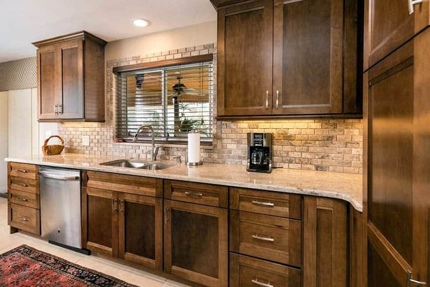 Kitchen with travertine tiles, windows with blinds and oakwood cabinets